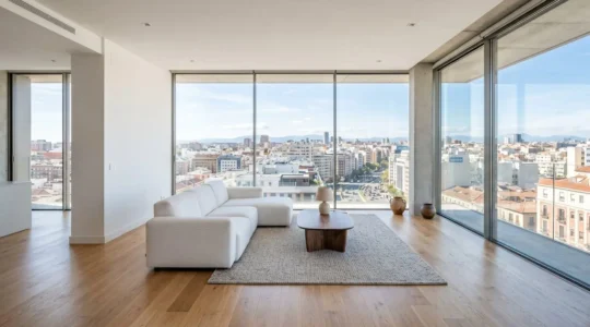 Salón contemporáneo español vacío con amplio ventanal mostrando el skyline urbano bajo luz natural del día